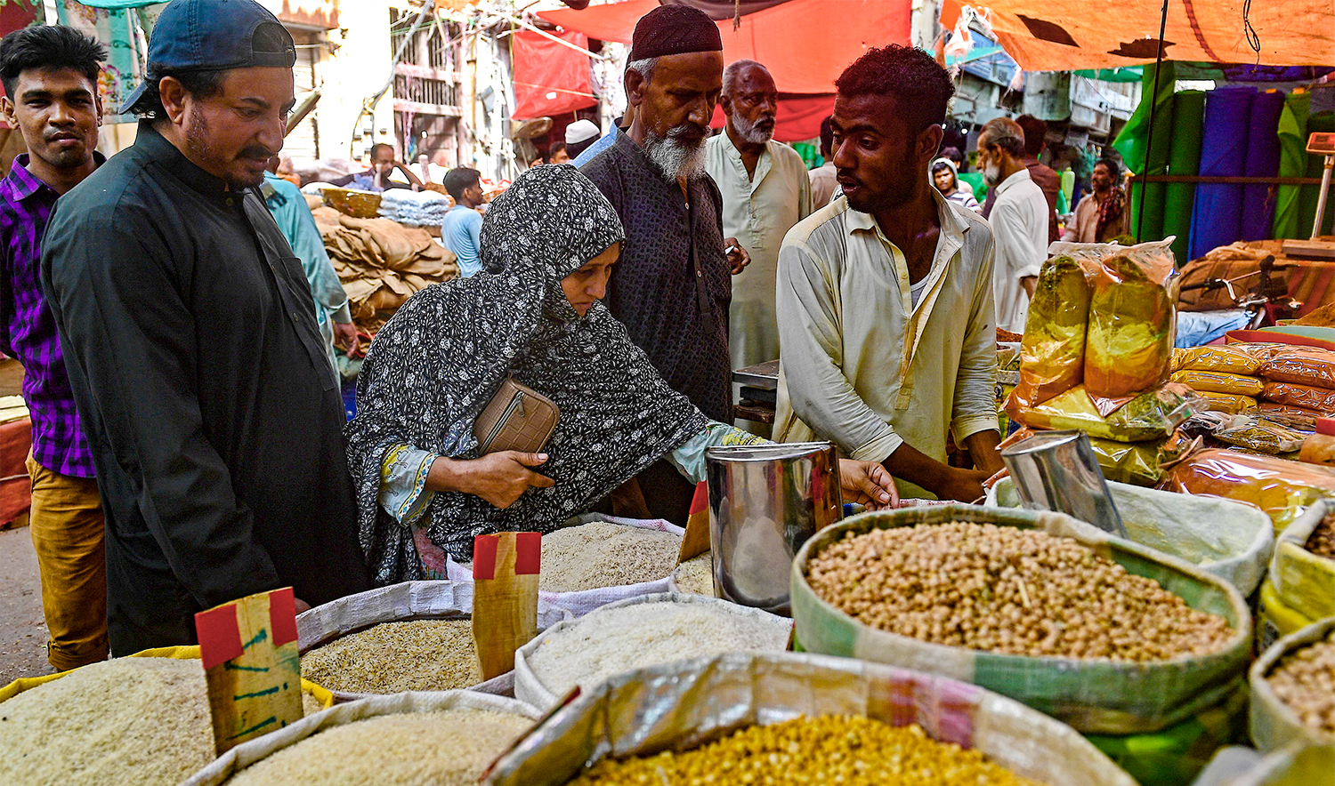 Customers bargain as they buy cereals and legumes at a shop in Karachi on June 8, 2023. (AFP/File)