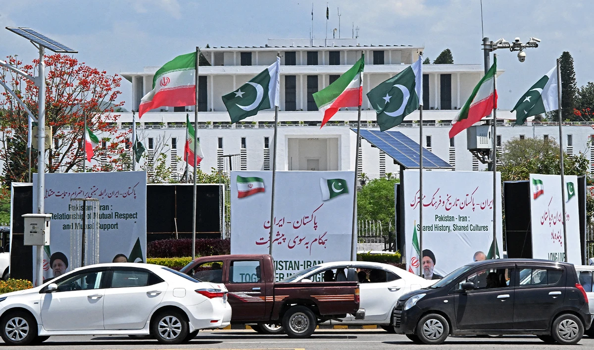 Commuters make their way past the welcoming billboards installed at the constitution avenue for the visit of late Iranian President Ebrahim Raisi, in Islamabad on April 22, 2024. (AFP/File)