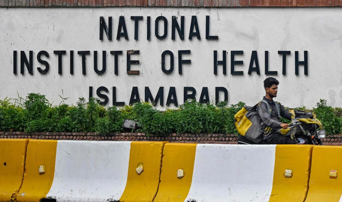 A delivery boy rides past the building of National Institute of Health (NIH), a Pakistani research institute mainly responsible for biomedical and health related research, in Islamabad on August 16, 2024. (AFP/File)