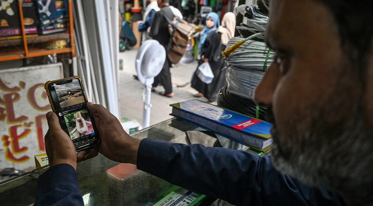 A man uses the social media platform X, formerly known as Twitter, on his phone at a market in Islamabad on April 17, 2024. (AFP/File)