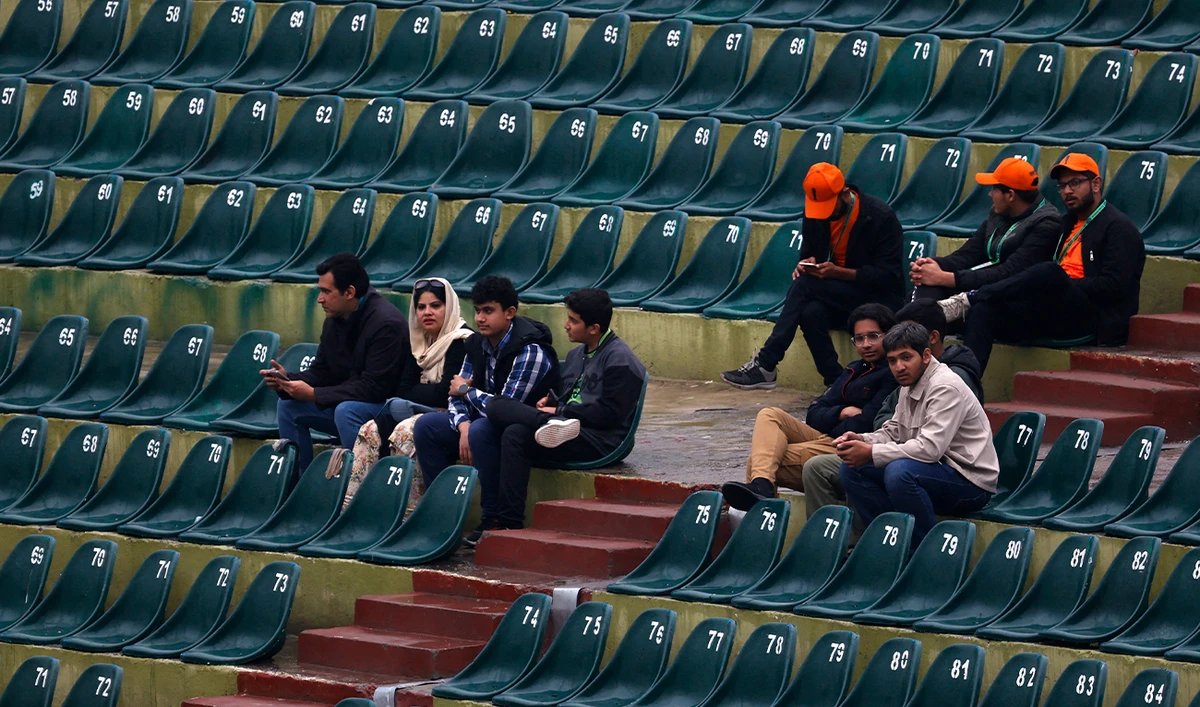 Fans wait as rain delays the start of the ICC Champions Trophy one-day international (ODI) cricket match between Pakistan and Bangladesh at the Rawalpindi Cricket Stadium in Rawalpindi on February 27, 2025. (Reuters)