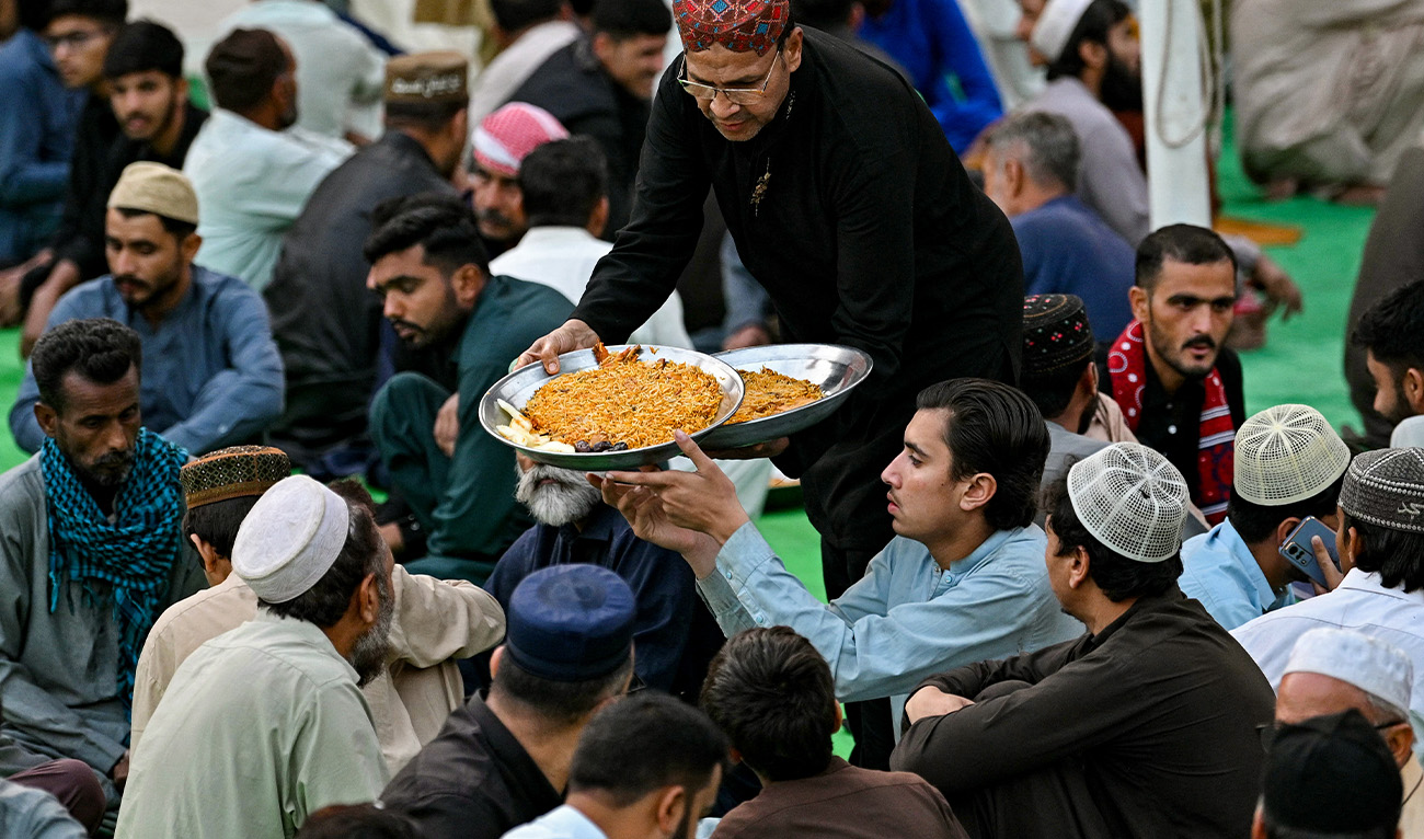 A volunteer distributes iftar meals to Muslims waiting to break their fast on the first day of the Islamic holy fasting month of Ramadan at Memon mosque in Karachi on March 2, 2025. (AFP)