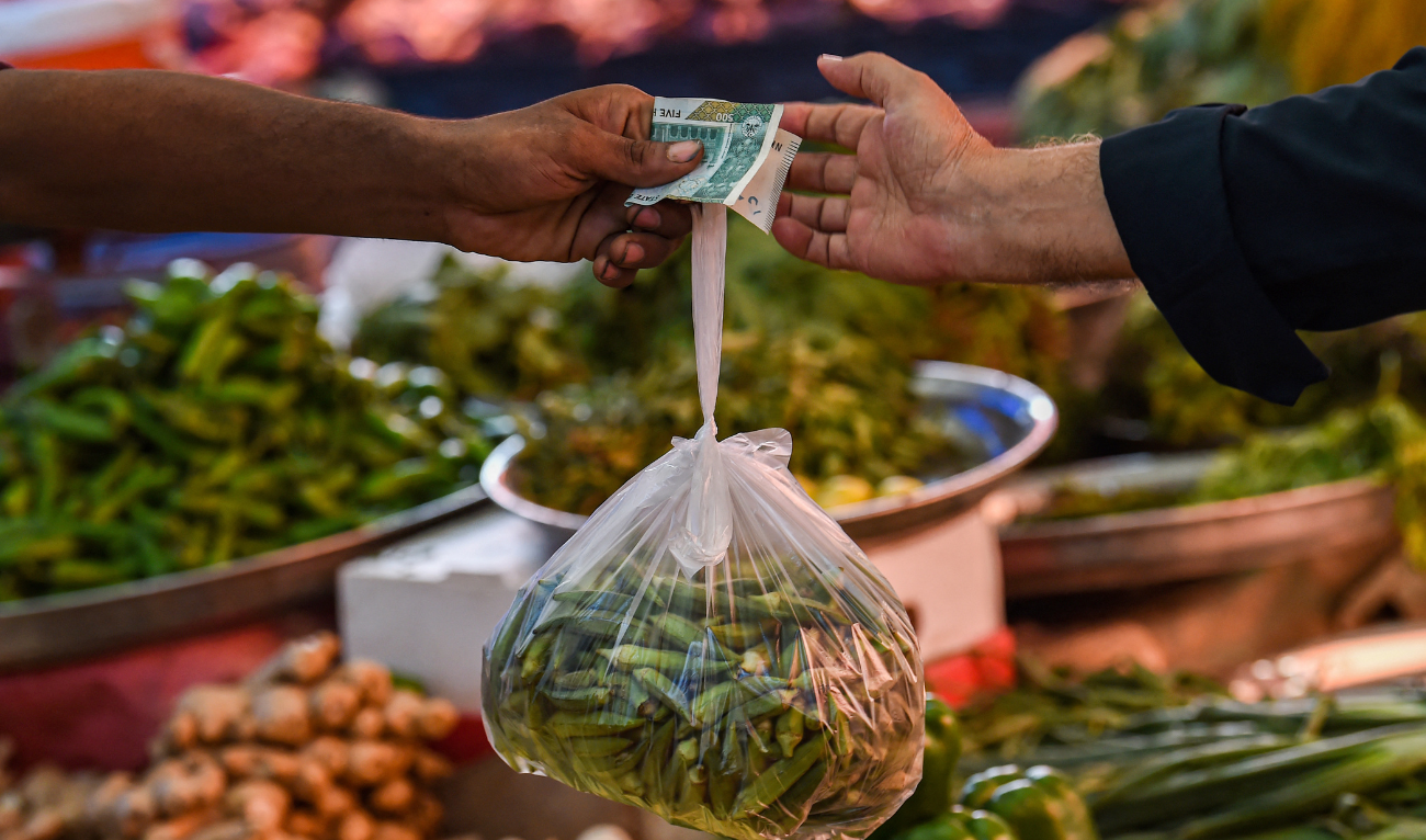 A customer buys vegetables from a stall at a market in Karachi on July 3, 2023. (AFP/file)