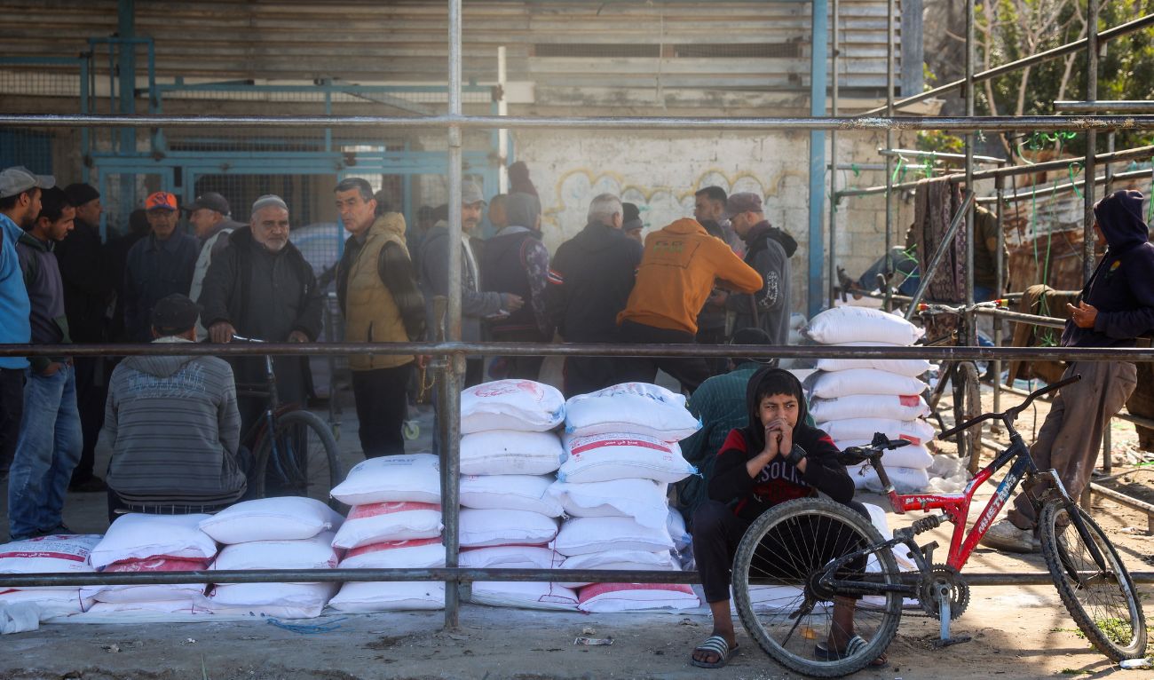 Palestinians queue to receive food aid from an UNRWA distribution center at the Nuseirat refugee camp in the central Gaza Strip on March 3, 2025. (AFP)