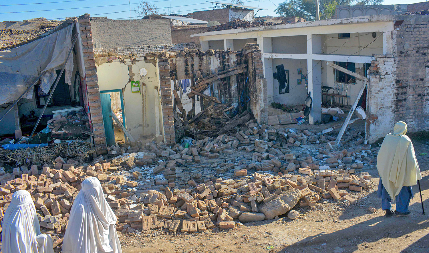 Women walk past the wreckage after militants detonated explosive-laden vans at an army compound in Bannu on March 5, 2025. (AFFP)