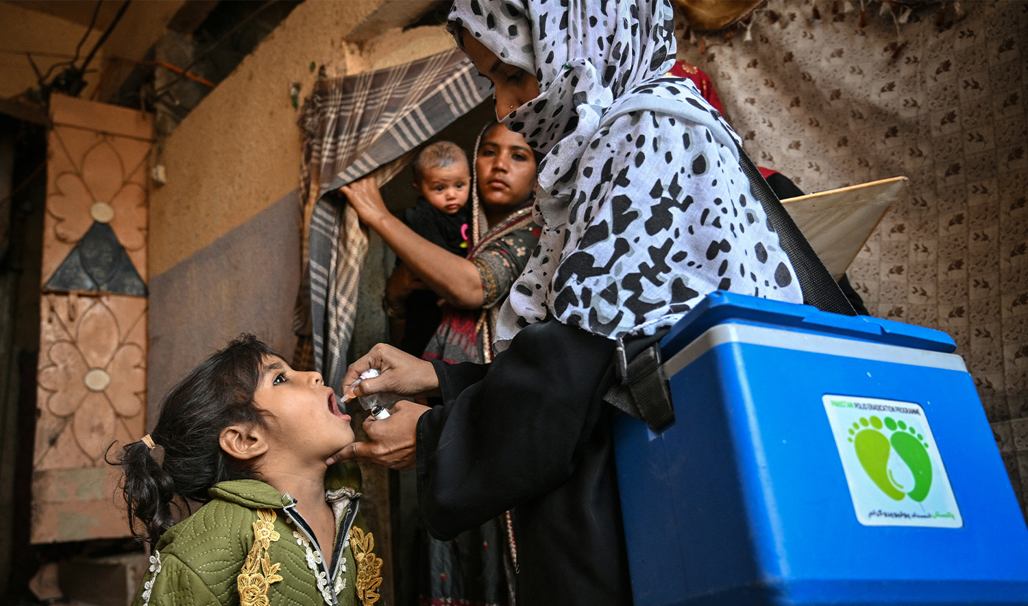 A health worker (R) administers polio drops to a child on the first day of a nationwide polio vaccination campaign, in Karachi on February 3, 2025. (AFP/File)