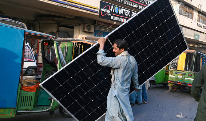 A worker carries a solar panel plate at a market in Lahore on June 12, 2024. (AFP/File)