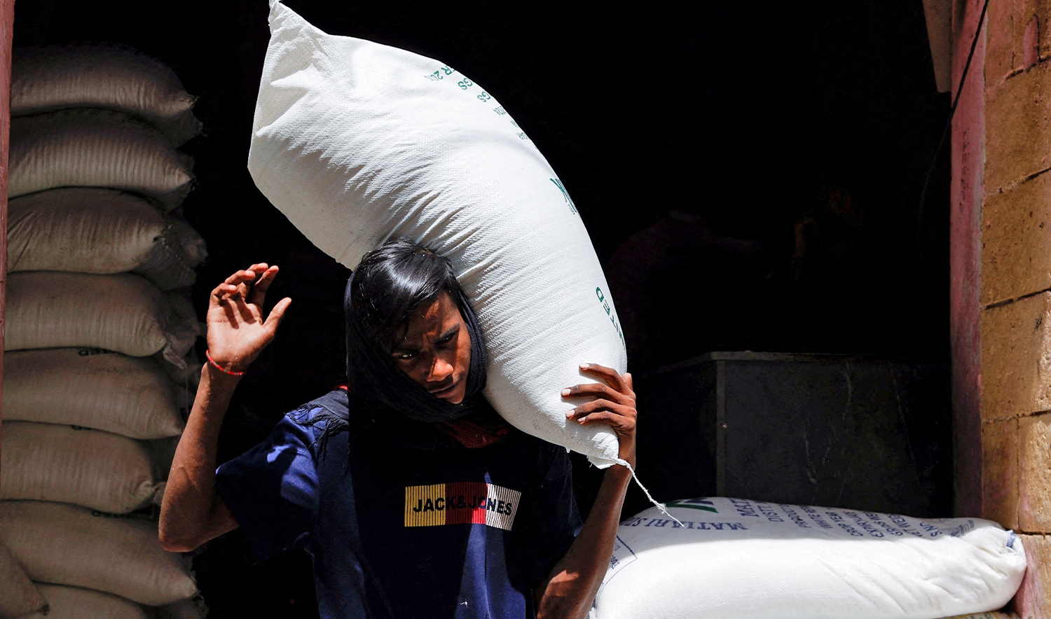 A labourer carries a sack of sugar while loading on a cart at a wholesale food and grain market in Karachi, Pakistan on June 12, 2024. (REUTERS/File)
