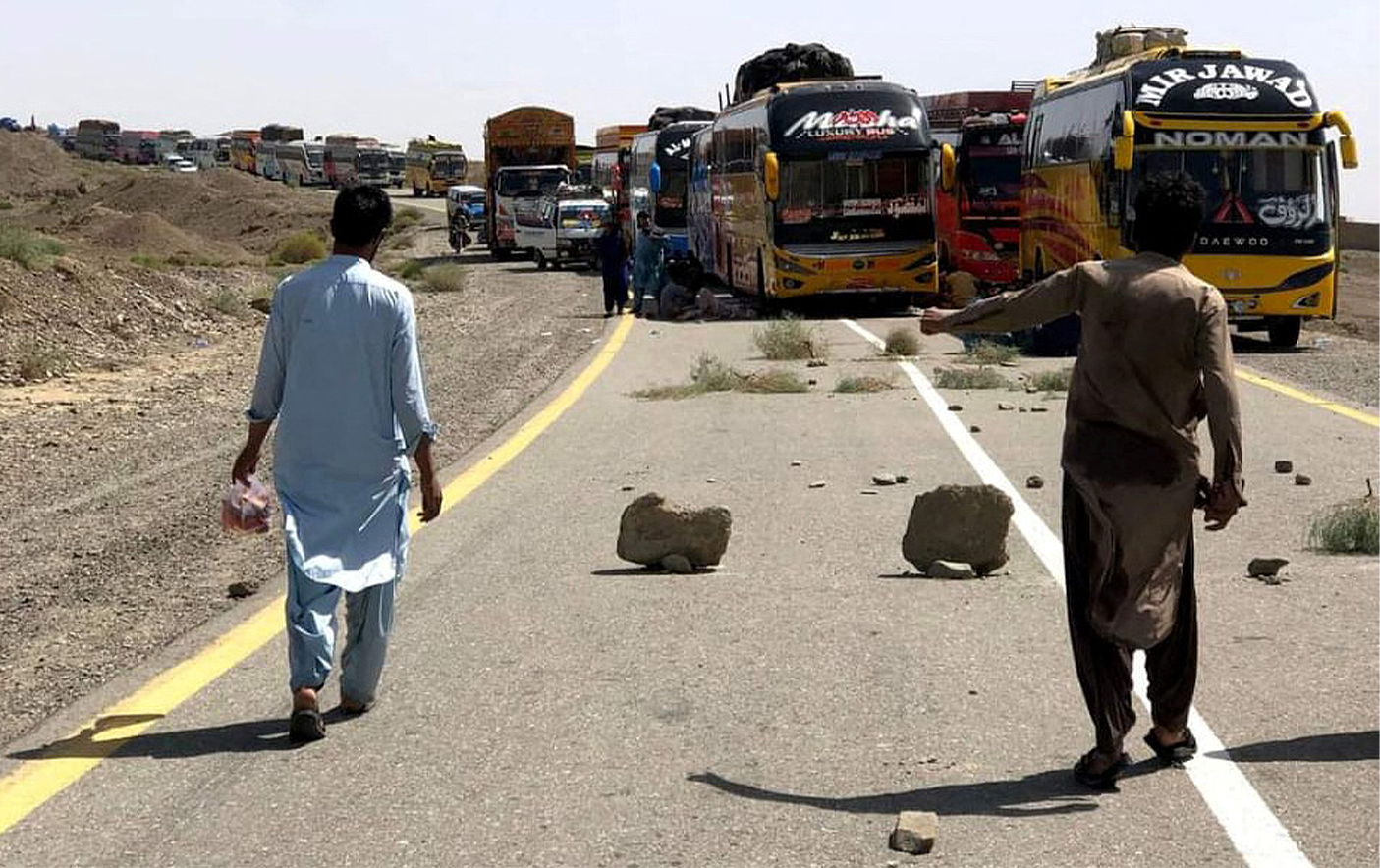 People walk past parked supply trucks alongside a road, after traffic was halted following an attack on a highway in Pakistan's restive province of Balochistan on August 26, 2024. (REUTERS/File)