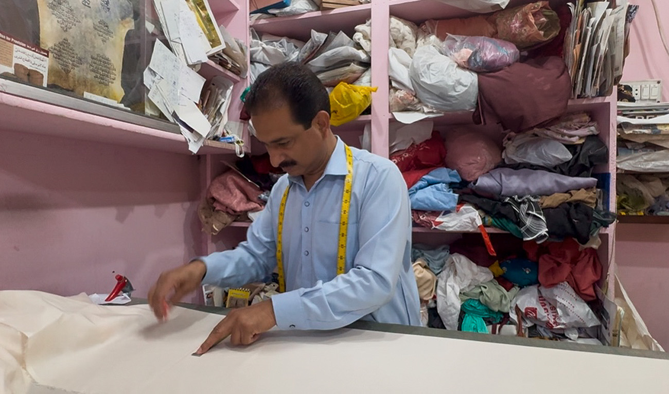 Tailor Muhammad Shafiq marks fabric for cutting at his shop in Islamabad, Pakistan on March 25, 2025. (AN Photo)