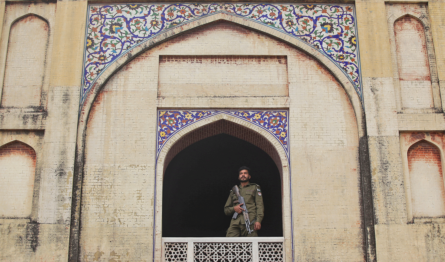 A police officer stands guard from the window of the Mughal era Wazir Khan mosque, as people attend Friday prayers during the fasting month of Ramadan in Lahore, Pakistan on May 17, 2019. (REUTERS/File)