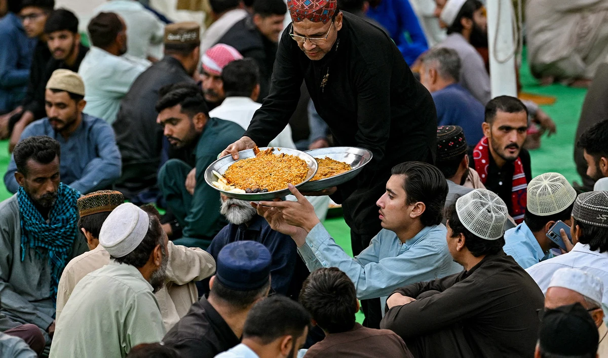 A volunteer distributes iftar meals to Muslims waiting to break their fast on the first day of the Islamic holy fasting month of Ramadan at Memon mosque in Karachi on March 2, 2025. (AFP)