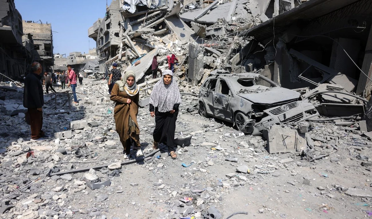 People walk amid the rubble of a building destroyed in an overnight Israeli strike in Jabalia, in the northern Gaza Strip on March 18, 2025. (AFP)