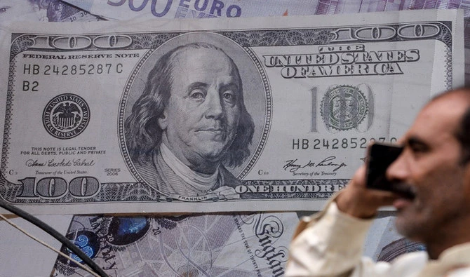 A man talks on the phone in front of a poster displaying US dollars at the currency exchange place in Lahore, Pakistan, on May 16, 2019. (AFP/File)