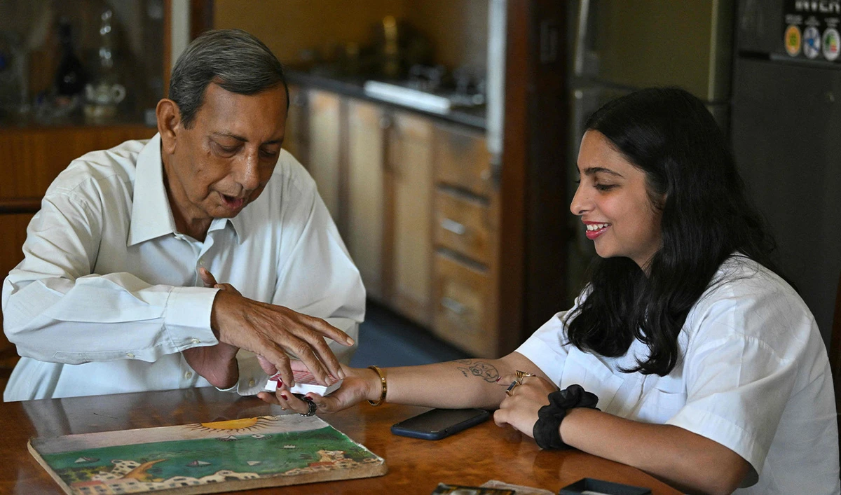 Elisha Amra (R) and her 76-year-old grandfather Kersi Umrigar play a card game at the latter's home in a Karachi enclave reserved for Zoroastrians on February 28, 2025 (AFP)