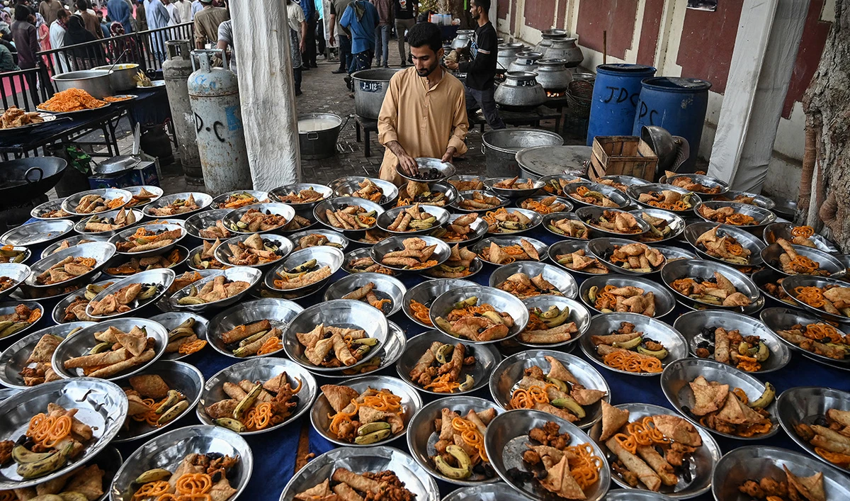 A volunteer arranges iftar meals prepared for Muslims waiting to break their fast during the Islamic holy fasting month of Ramadan in Karachi on March 5, 2025. (AFP)