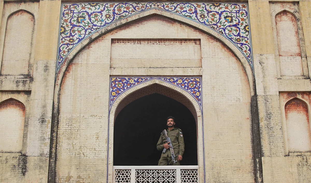 A police officer stands guard from the window of the Mughal era Wazir Khan mosque, as people attend Friday prayers during the fasting month of Ramadan in Lahore, Pakistan on May 17, 2019. (REUTERS/File)