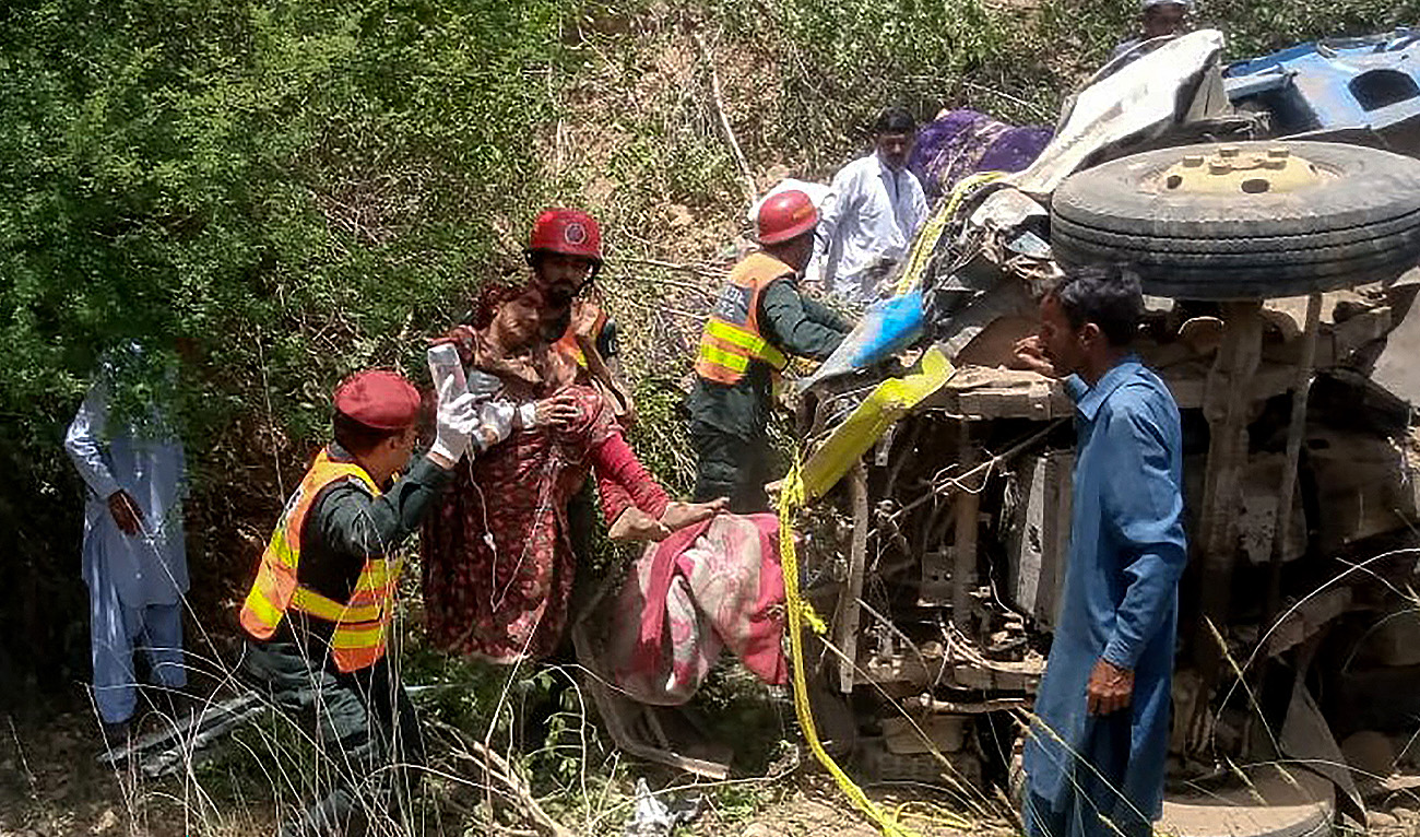 This handout photograph taken and released by Pakistan's Punjab Emergency Service (Rescue 1122) on May 18, 2024 shows rescue workers carrying an injured woman following a road accident in Khushab district of Pakistan's Punjab province after a truck carrying a family and children plunged into a ravine. (AFP/File)
