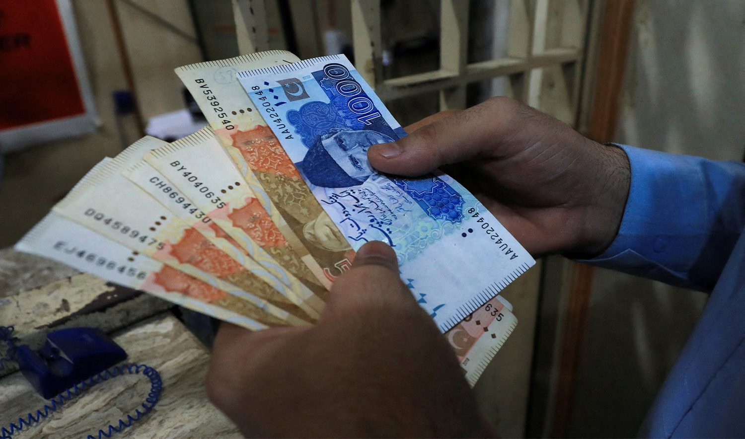 man counts Pakistani rupee notes at a currency exchange shop in Peshawar, Pakistan, on September 12, 2023. (REUTERS)
