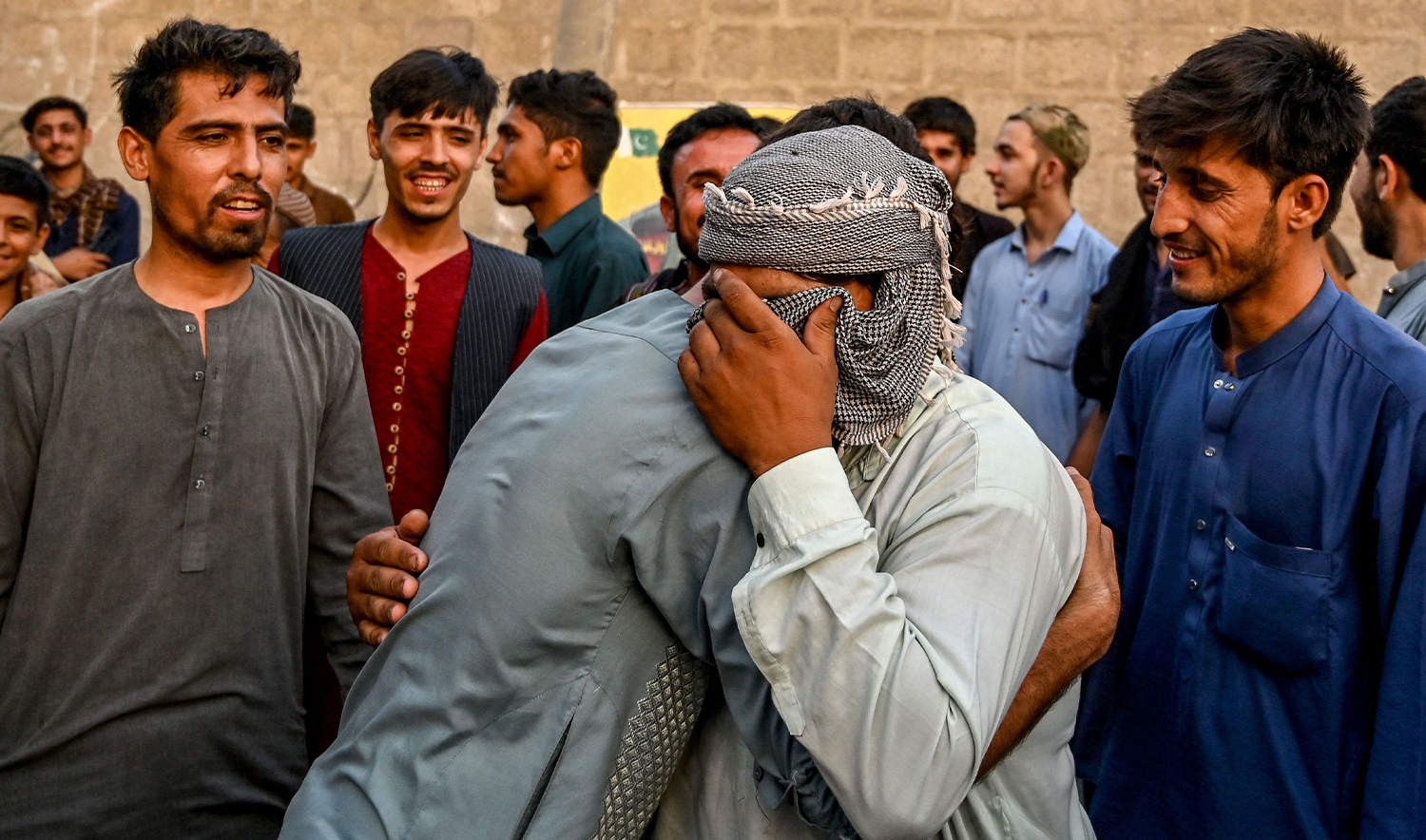 Afghan refugees embrace each other before leaving for Afghanistan at a bus stand in Karachi on April 8, 2025. (AFP)
