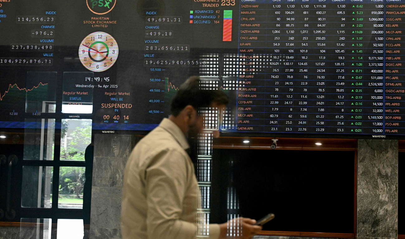 A stockbroker walks past share prices on a financial market board during a trading session at the Pakistan Stock Exchange (PSX) in Karachi on April 9, 2025. (AFP)