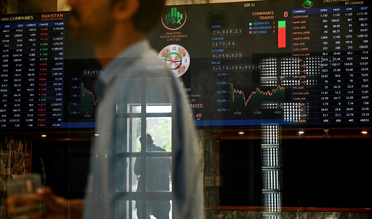 A stockbroker walks past share prices on a financial market board during a trading session at the Pakistan Stock Exchange (PSX) in Karachi on April 9, 2025. (AFP)