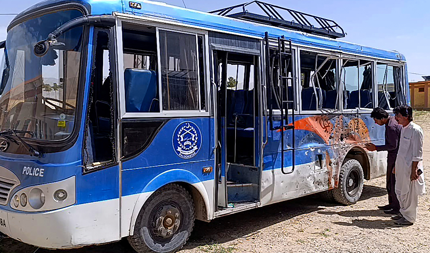 People look at a damaged police bus parked in a security compound following a bomb explosion in Mastung district on April 15, 2025. (AFP)