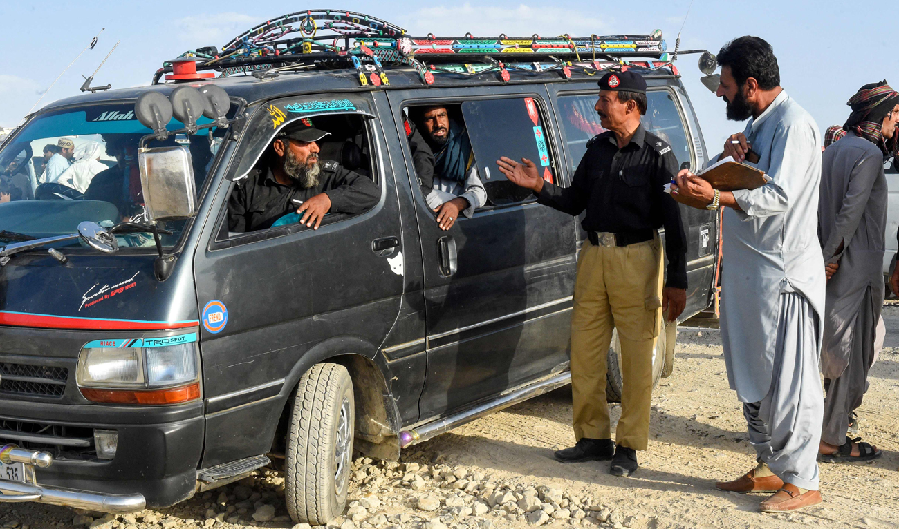 Policemen escort vans carrying Afghan refugees from a camp in Panjpai area on the outskirts of Quetta on April 16, 2025. (AFP)
