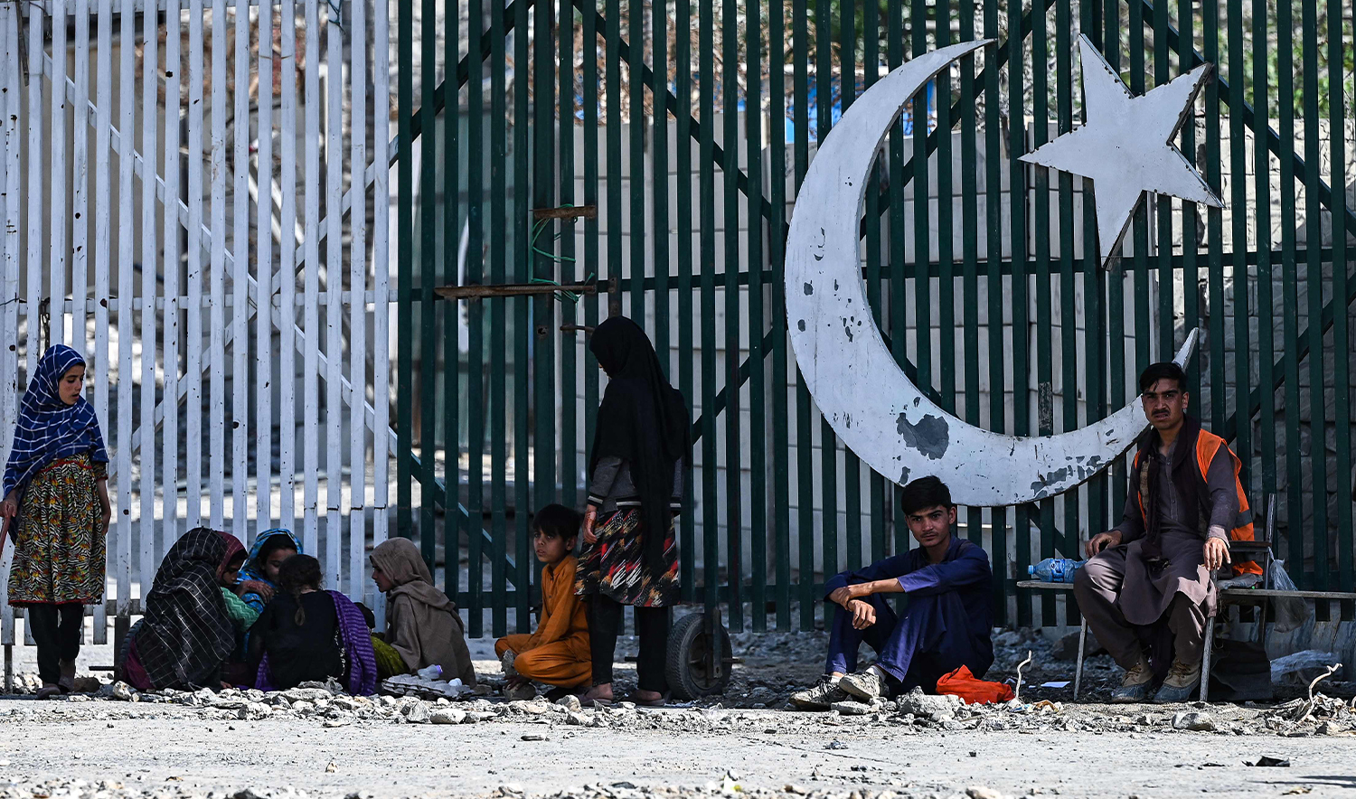 Afghan workers sit near the zero point at the Torkham International Border Crossing between Afghanistan and Pakistan, in Nangarhar province, on April 20, 2025. (AFP)