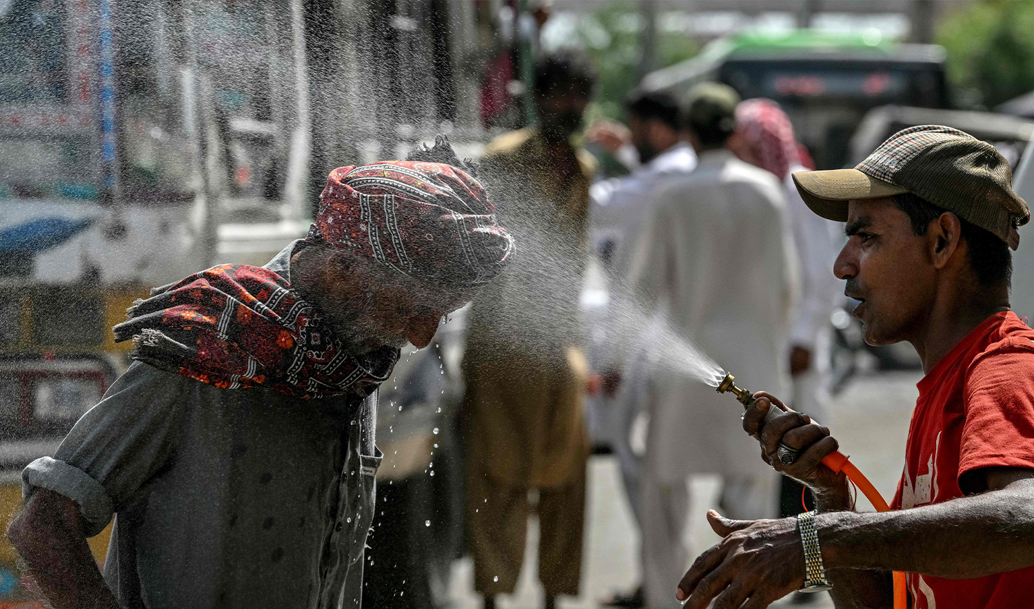 A volunteer of the Edhi Foundation sprays water on a passerby's head to cool off on a hot summer day along a road amid the ongoing heatwave in Karachi on April 21, 2025. (AFP)