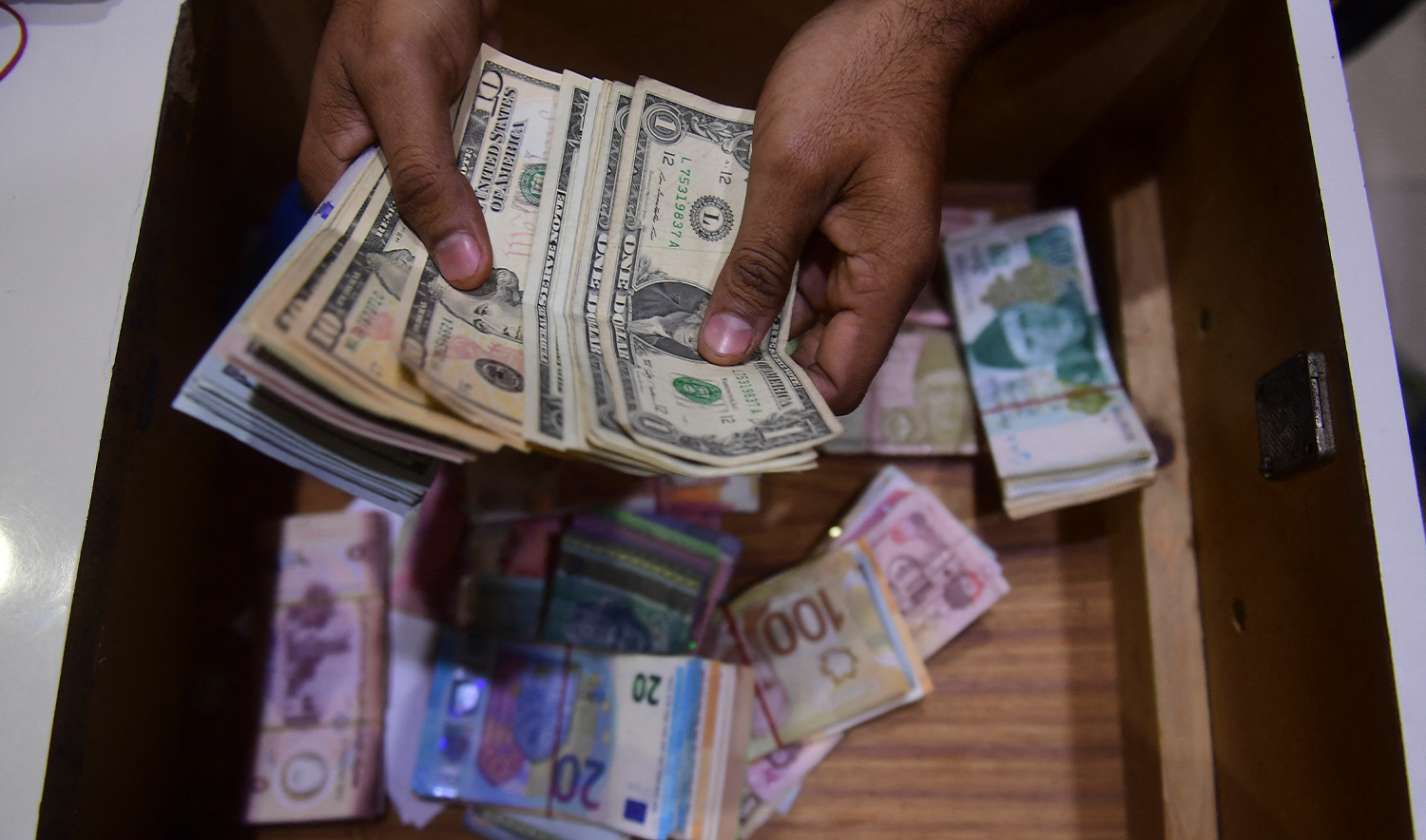 A dealer counts US dollars at a money exchange market in Karachi on January 27, 2023. (AFP/File)
