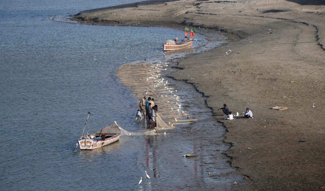 Fishermen clear a fishing net in the water on the partially dried up riverbed of the Indus River in Hyderabad, Pakistan on April 25, 2025. (REUTERS)