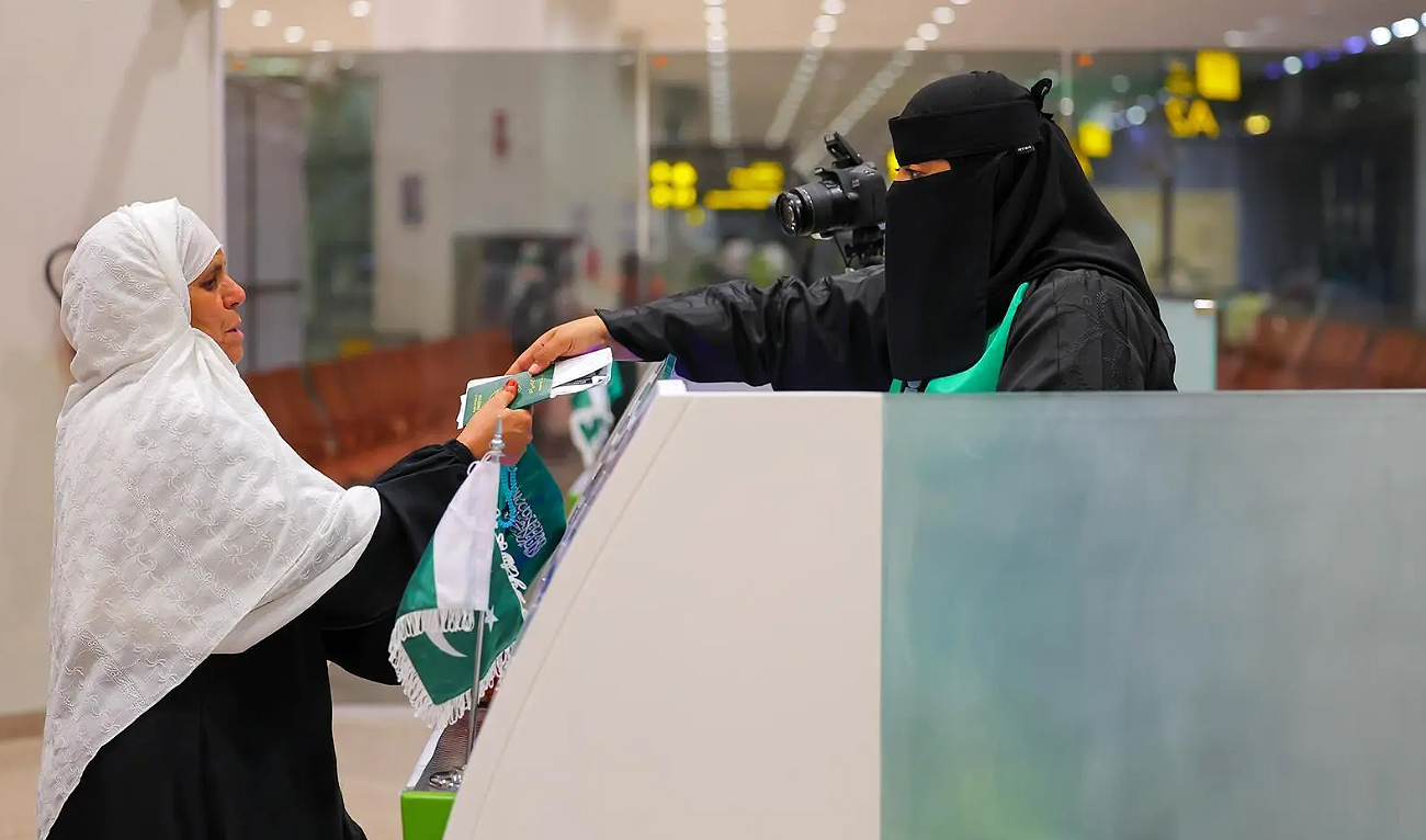 Saudi immigration officer hands Pakistani pilgrim her passport on Makkah Route initiatives’ immigration counter at the Islamabad International Airport in Islamabad on April 29, 2025. (SPA)