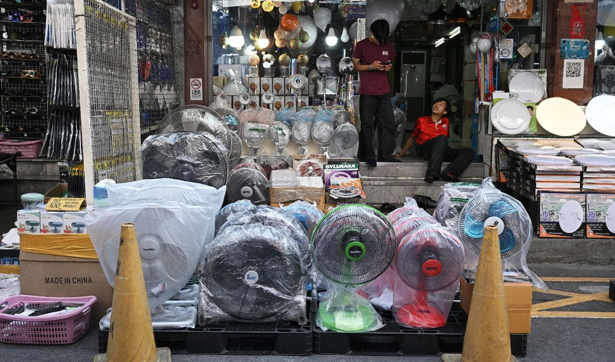 Store workers wait for customers behind a row of fans for sale to combat the heat at an electrical appliances store in Bangkok on March 29, 2024. (AFP/ File)