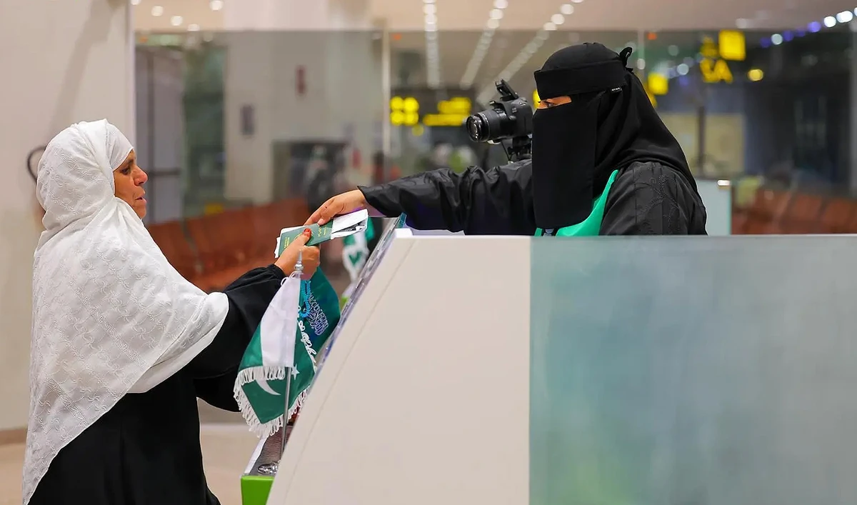 Saudi immigration officer hands Pakistani pilgrim her passport on Makkah Route initiatives’ immigration counter at the Islamabad International Airport in Islamabad on April 29, 2025. (SPA)