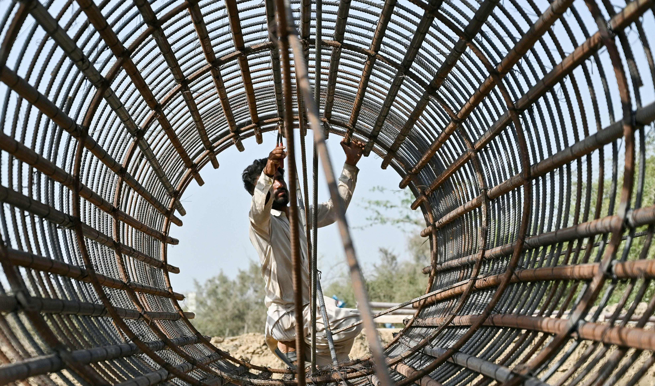 A Construction worker fixes iron frame of a foundation pillar for a bridge under construction in Karachi on April 30, 2025, on the eve of International Labour Day. (AFP)