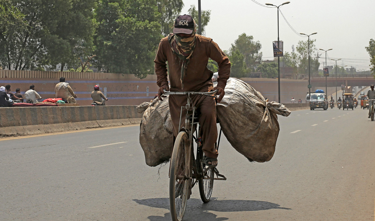 A cyclist rides through a street on a hot summer day in Multan on May 1, 2025. (AFP)