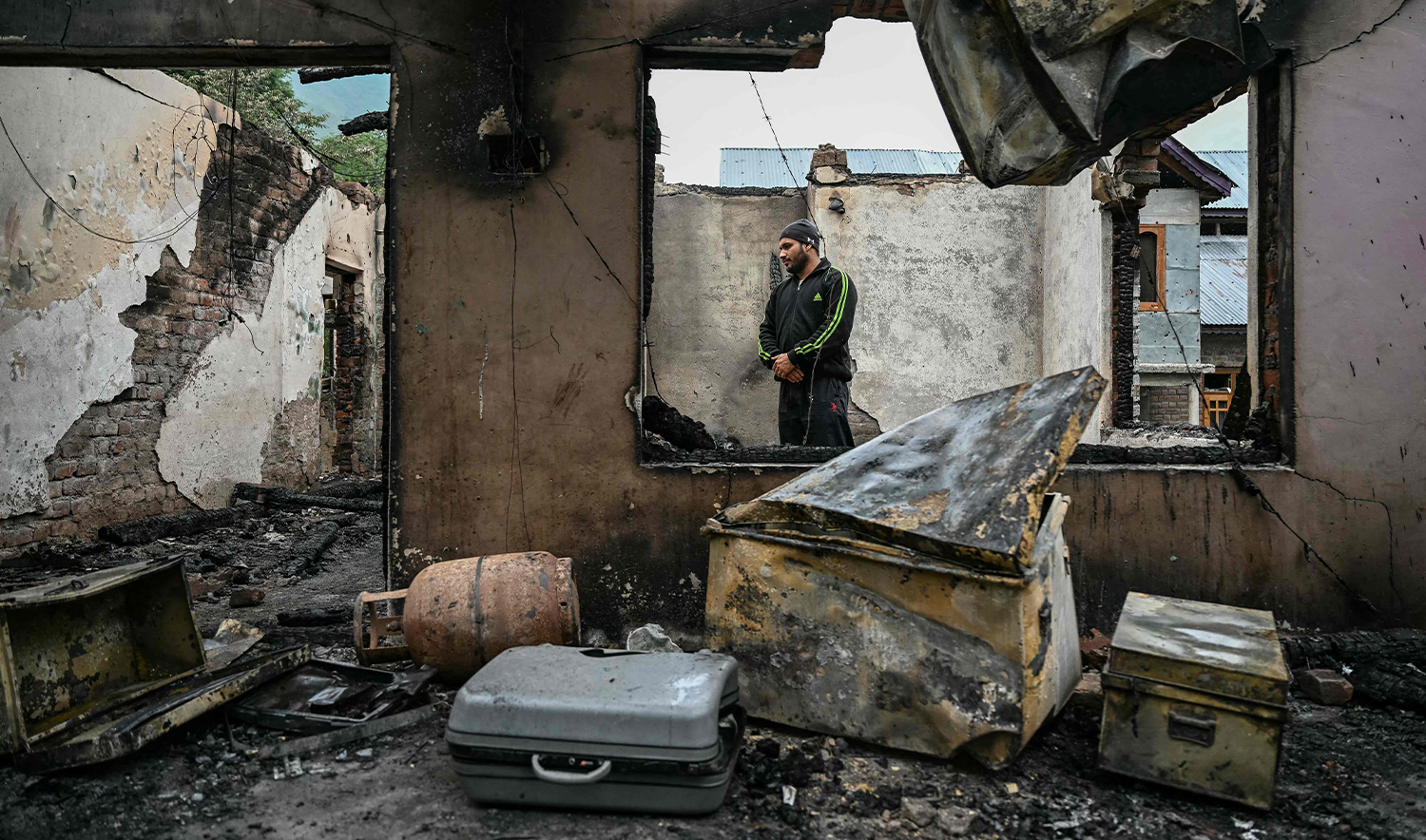 A man stands inside his house destroyed by artillery shelling at the Salamabad village in Uri, about 110kms from Srinagar in Indian-administered Kashmir, on May 8, 2025. (AFP)