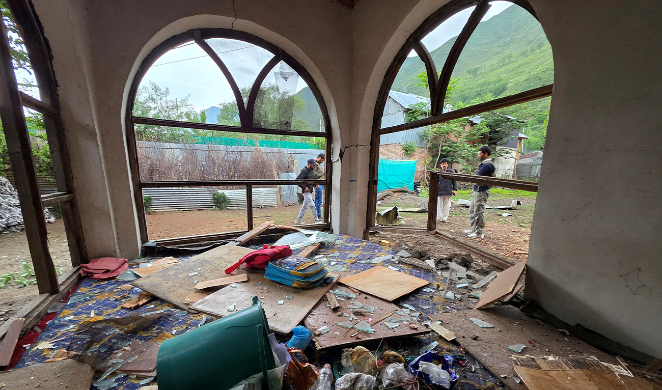 Men are seen through windowpanes of a residential house damaged by cross-border shelling in Gingal village near the Line of Control (LoC) between India and Pakistan, in Indian administrated Kashmir on May 9, 2025. (AFP)