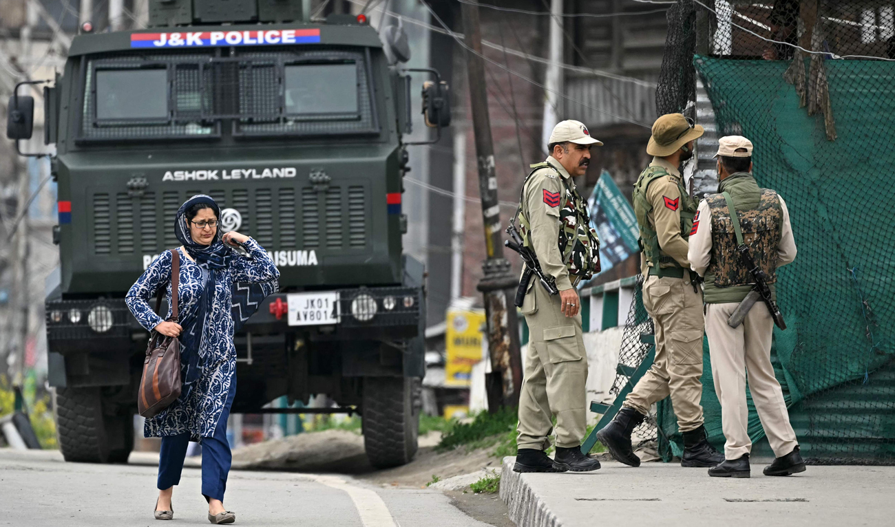 Indian policemen stand guard as a woman walks along a street in Srinagar on May 9, 2025. (AFP)