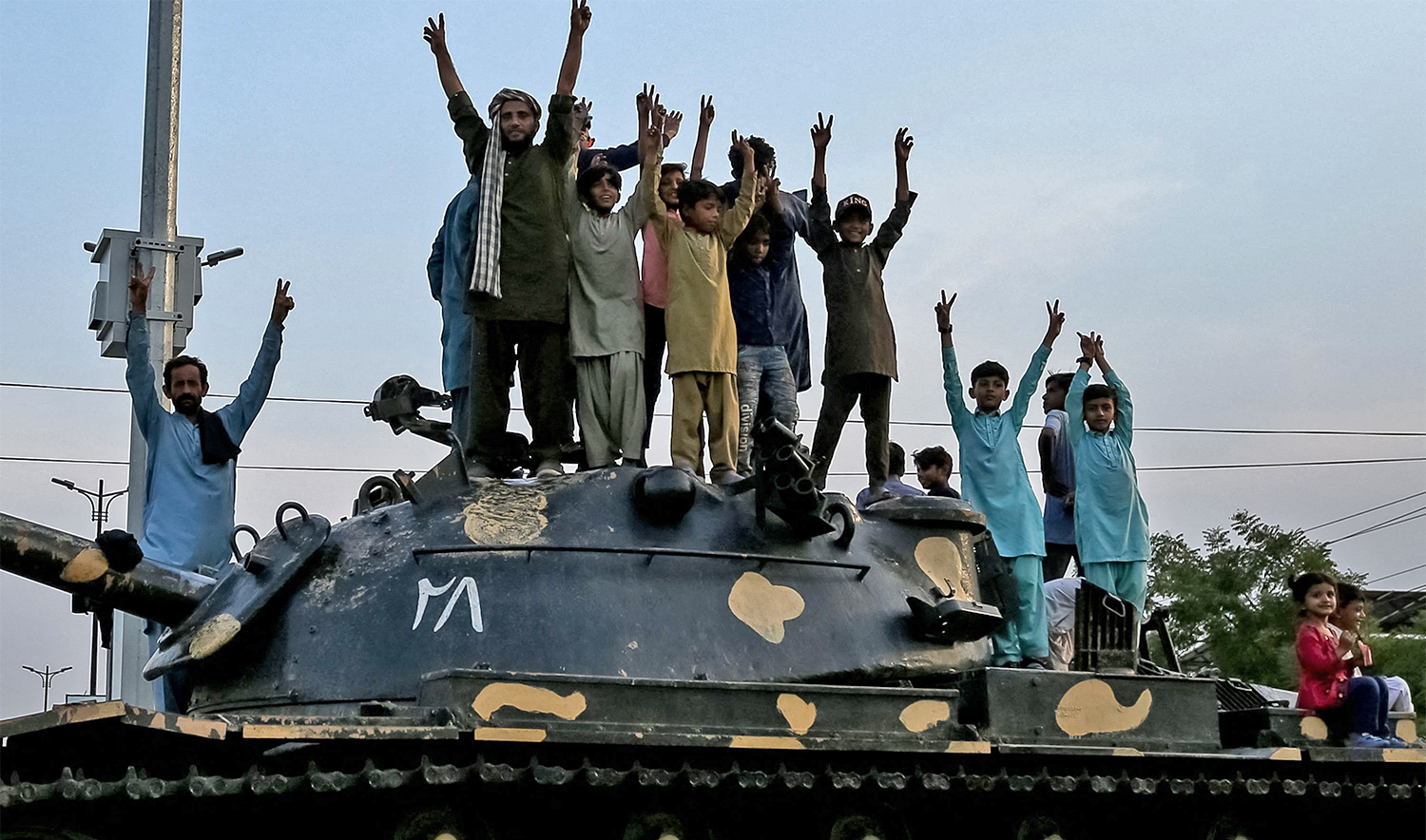 Pakistani people flashing victory signs stand over a tank as they celebrate after the ceasefire between Pakistan and India, in Multan on May 10, 2025. (AFP)