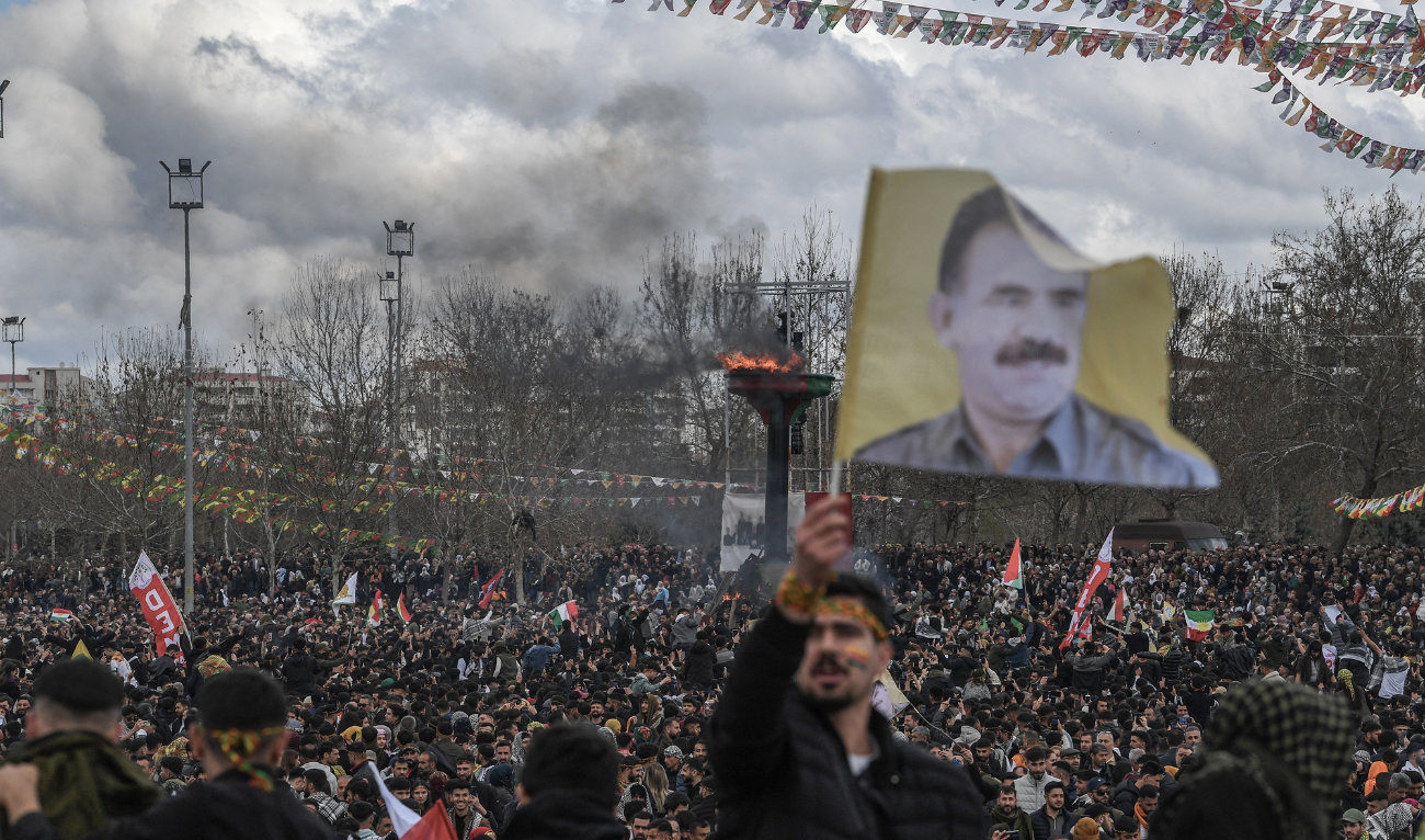 A man waves a flag depicting Abdullah Ocalan, Turkish-jailed founder of the Kurdistan Workers' Party (PKK) next to a bonfire during a gathering for Nowruz (aka Noruz or Newroz) celebrations marking the New Year of the Persian calendar and the first day of spring in Diyarbakir, south-eastern Turkey, on March 21, 2025. (AFP/ file)