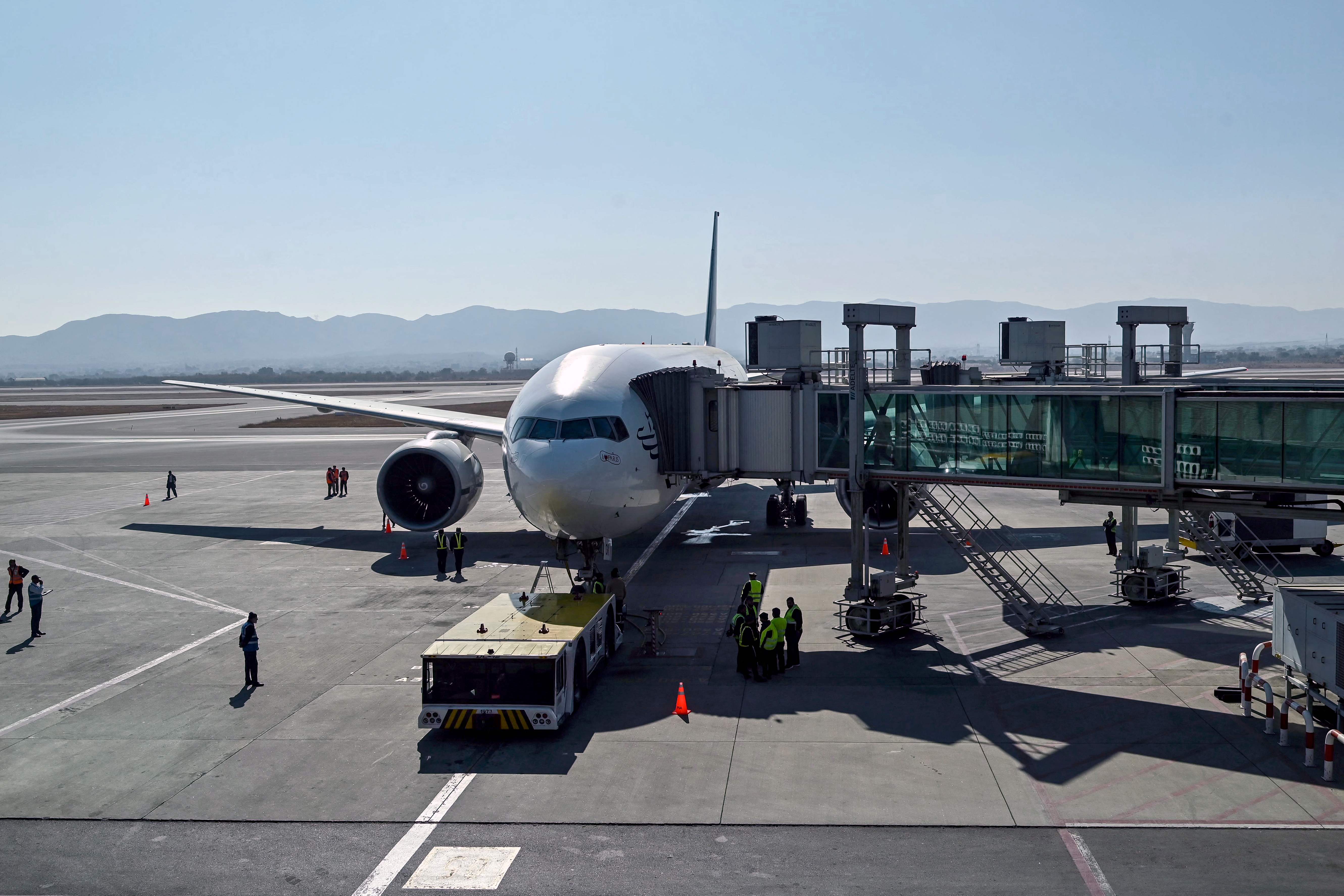 Ground staff stand next to the Pakistan International Airline (PIA) aircraft ahead of its takeoff for Paris at the Islamabad International Airport on January 10, 2025. (AFP/File)