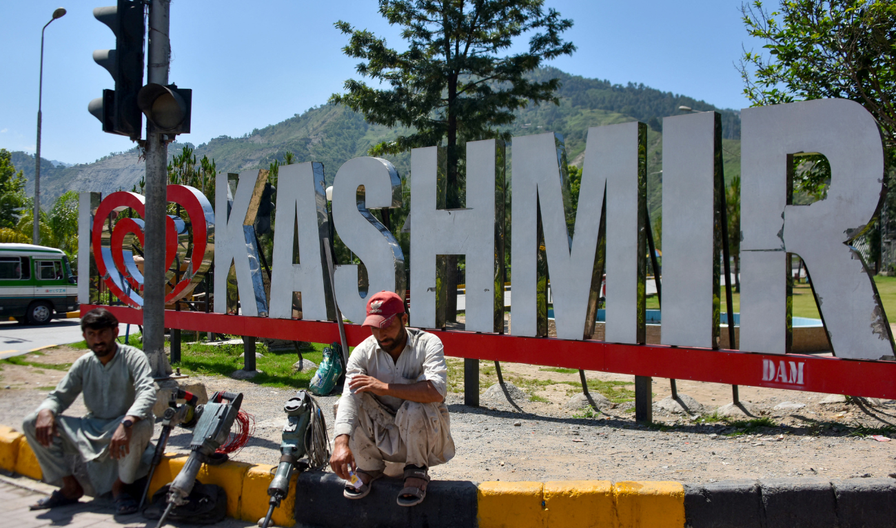 Workers wait along a road in Muzaffarabad, the capital of Pakistan-administered Kashmir, on May 14, 2025. (AFP)