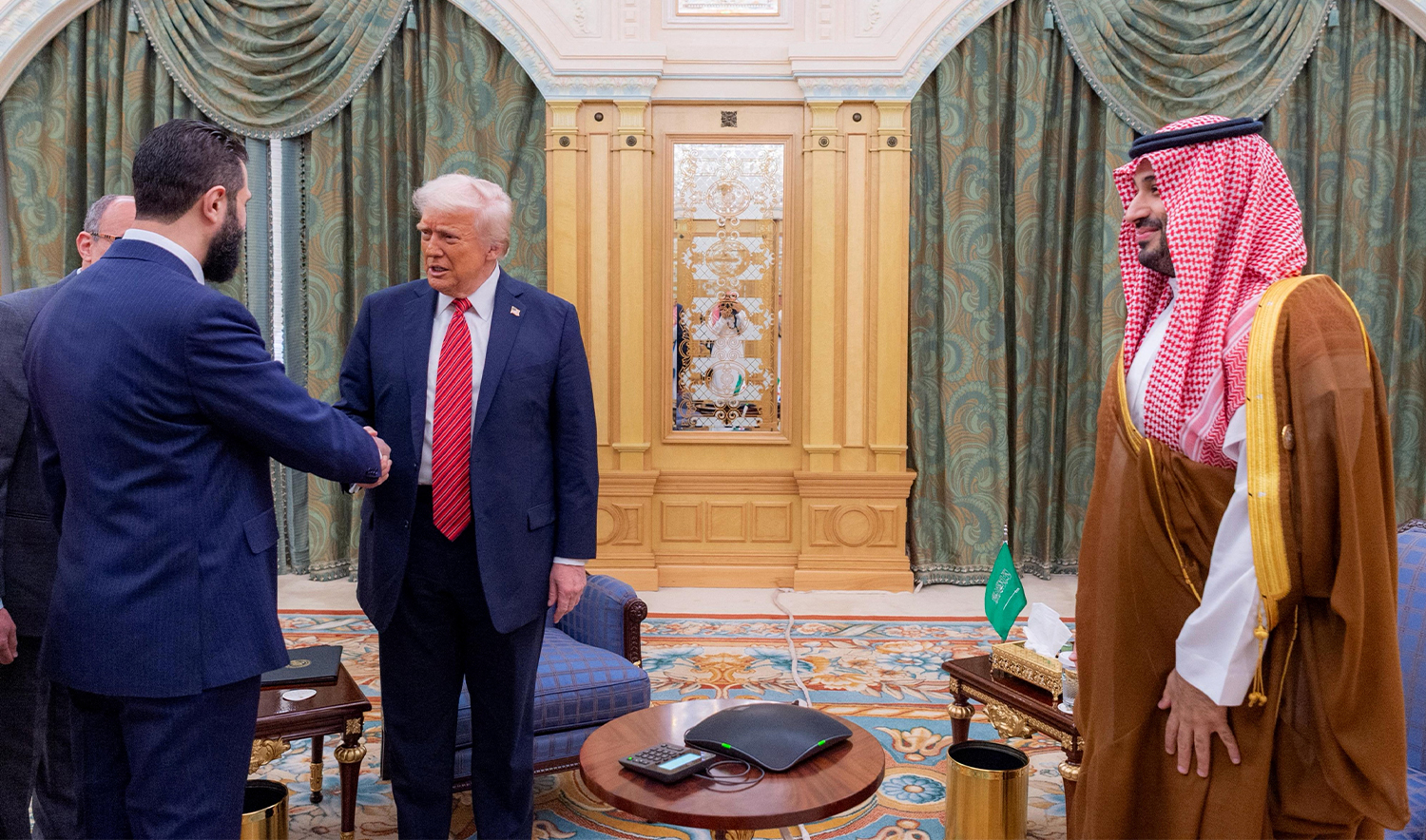 A handout picture provided by the Saudi Royal Palace shows Saudi Crown Prince Mohammed bin Salman (R) watching as US President Donald Trump (C) shakes hands with Syria's interim president Ahmed al-Sharaa in Riyadh on May 14, 2025. (AFP/Saudi Royal Palace)