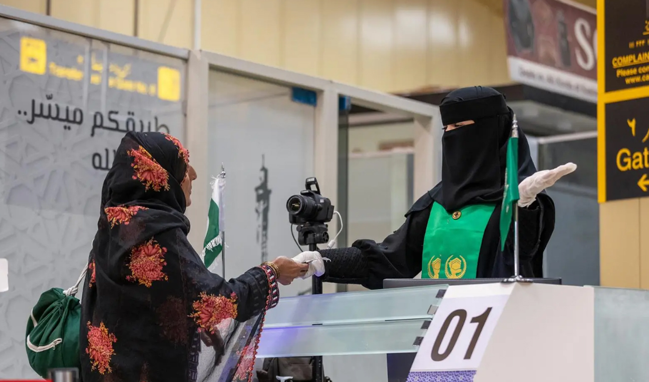 A Saudi officer hands a Pakistani pilgrim her passport at the Makkah Route immigration counter at the Jinnah International Airport in Karachi, Pakistan on May 15, 2025. (SPA)