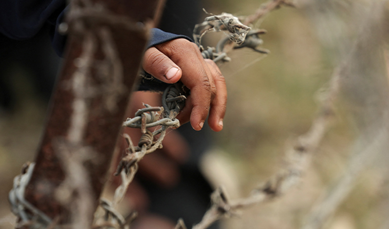 A child from Pakistan places his hand on barbed wire as he waits to go to Pakistan at the Attari-Wagah border crossing, after India revoked visas and suspended visa services to Pakistani citizens, following an attack on tourists near Pahalgam in south Kashmir, near Amritsar, India May 1, 2025. (Reuters/File)