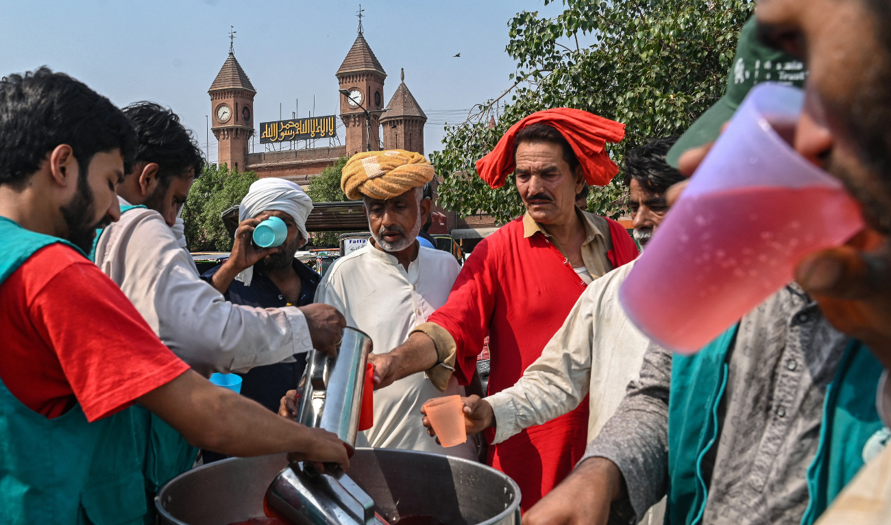 Volunteers distribute cold drinks to bypassers at a 'heatwave relief camp' along the road during a hot summer day in Lahore on May 31, 2024. (AFP/ File)
