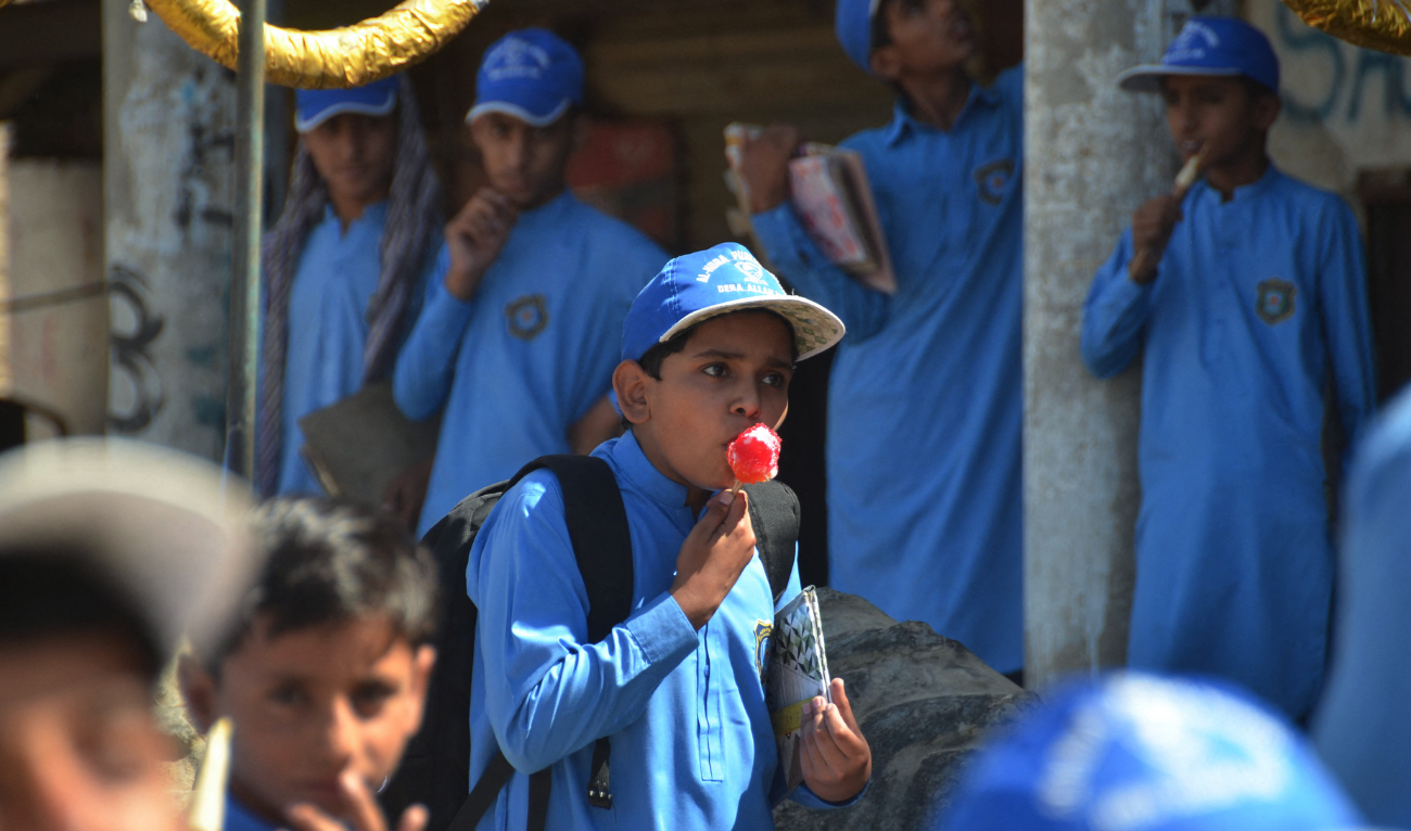 A school boy eats an ice gola (a street dessert made of crushing ice and syrups) outside his school during a hot summer day in Jaffarabad, in Pakistan's Balochistan province on May 29, 2024, amid the ongoing heatwave. (AFP/ file)