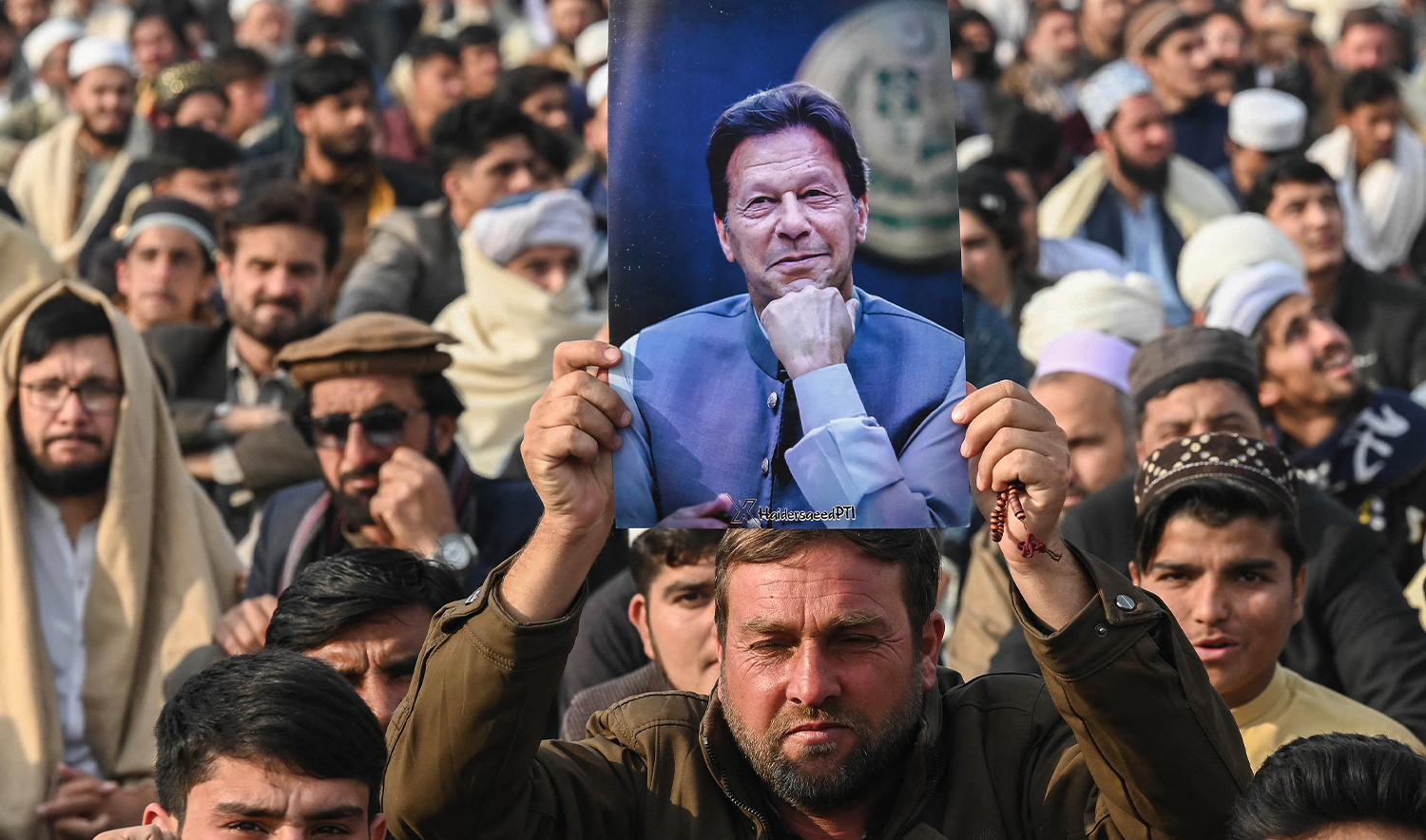 A supporter of jailed former prime minister Imran Khan holds his poster during a gathering by the Pakistan Tehreek-e-Insaf (PTI) party to observe Martyrs' Day to honour those who allegedly died during last month's protest, in Peshawar on December 15, 2024. (AFP/File)